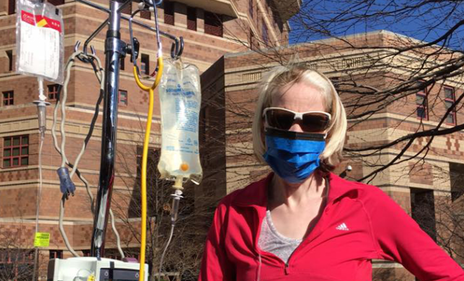 Carolyn standing outside with an IV pole wearing a mask.