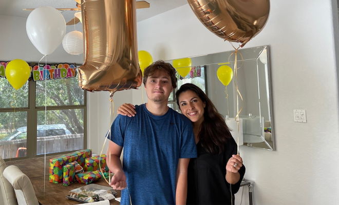 Bianca smiling with her son, standing in a kitchen decorated for his 18th birthday.