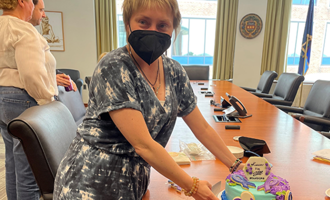 Anna wearing a mask holding a celebratory cake for one year of having cancer.