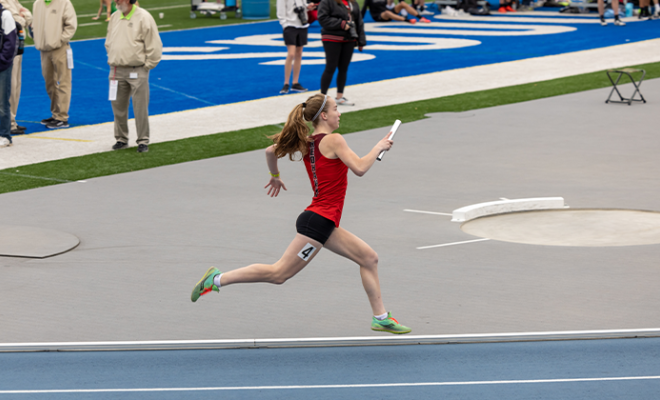 Grace running on a track with a baton.