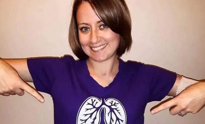 Ashley smiling and pointing to her purple t-shirt, which features a white graphic of lungs