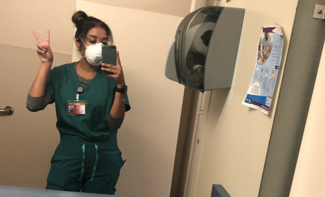 Daniela Cortez taking a selfie in scrubs in the mirror of a bathroom